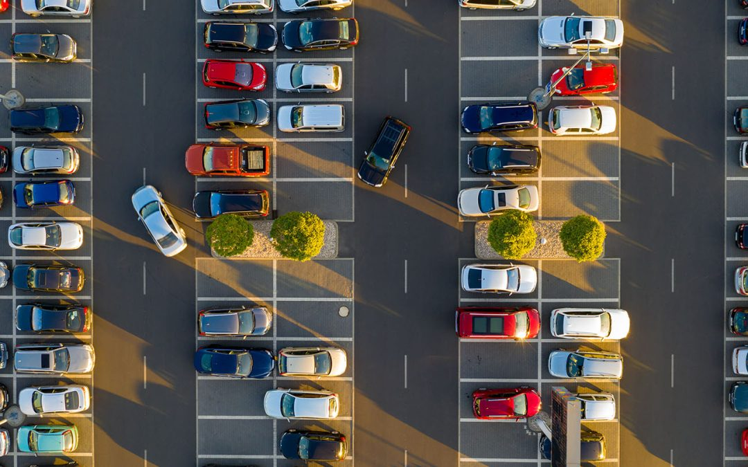 Overhead view of cars and open parking spaces in warm evening light.